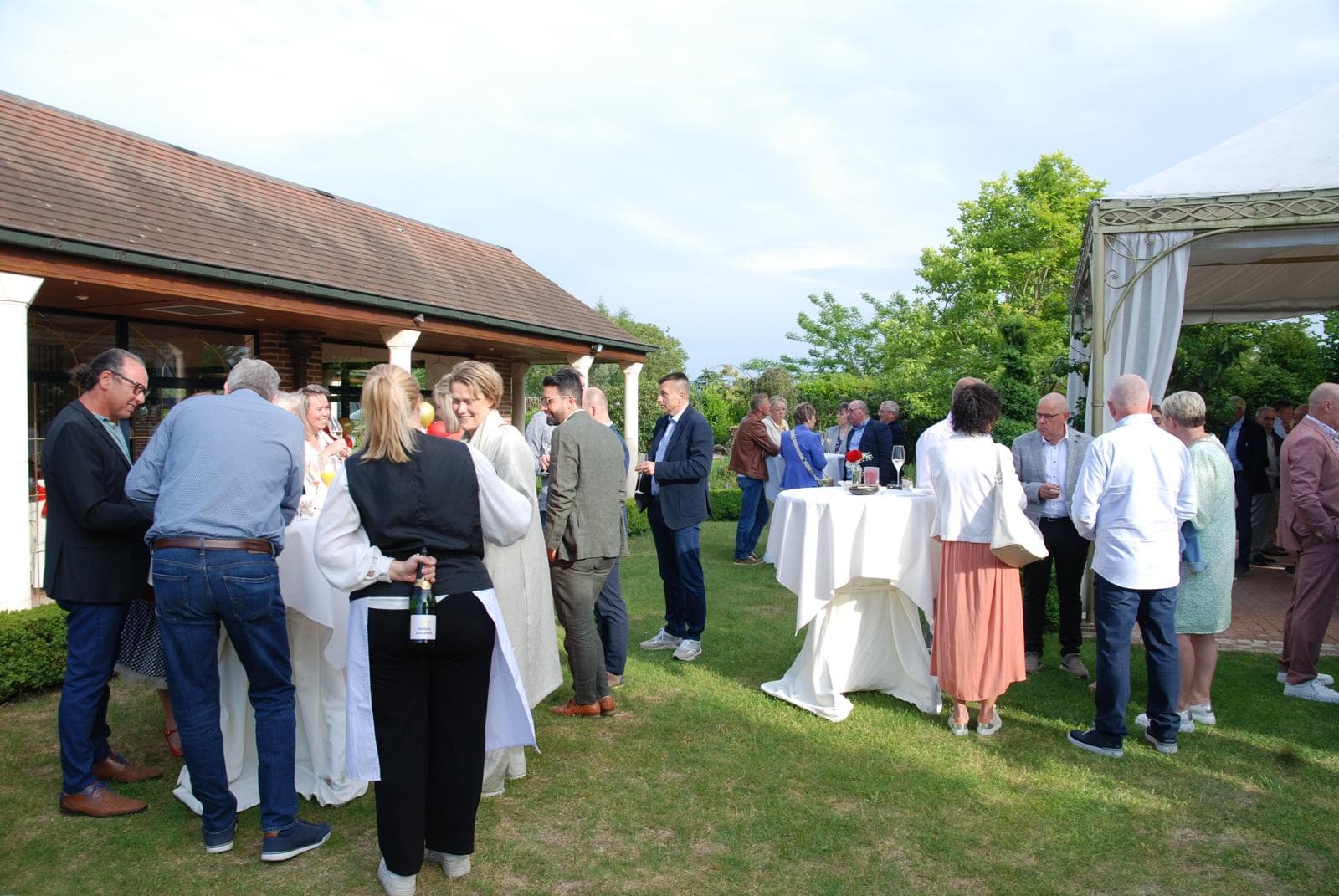 Gasten op een tuinreceptie met champagne — warme sfeer bij een outdoor bruiloft of event van The ID.