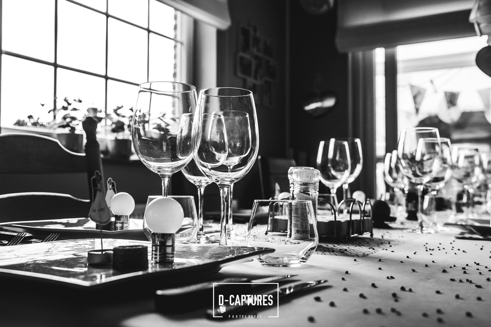 Formele bruiloftstafel met wijnglazen en gedekte borden — verzorgde receptiestyling van The ID, zwart-wit.